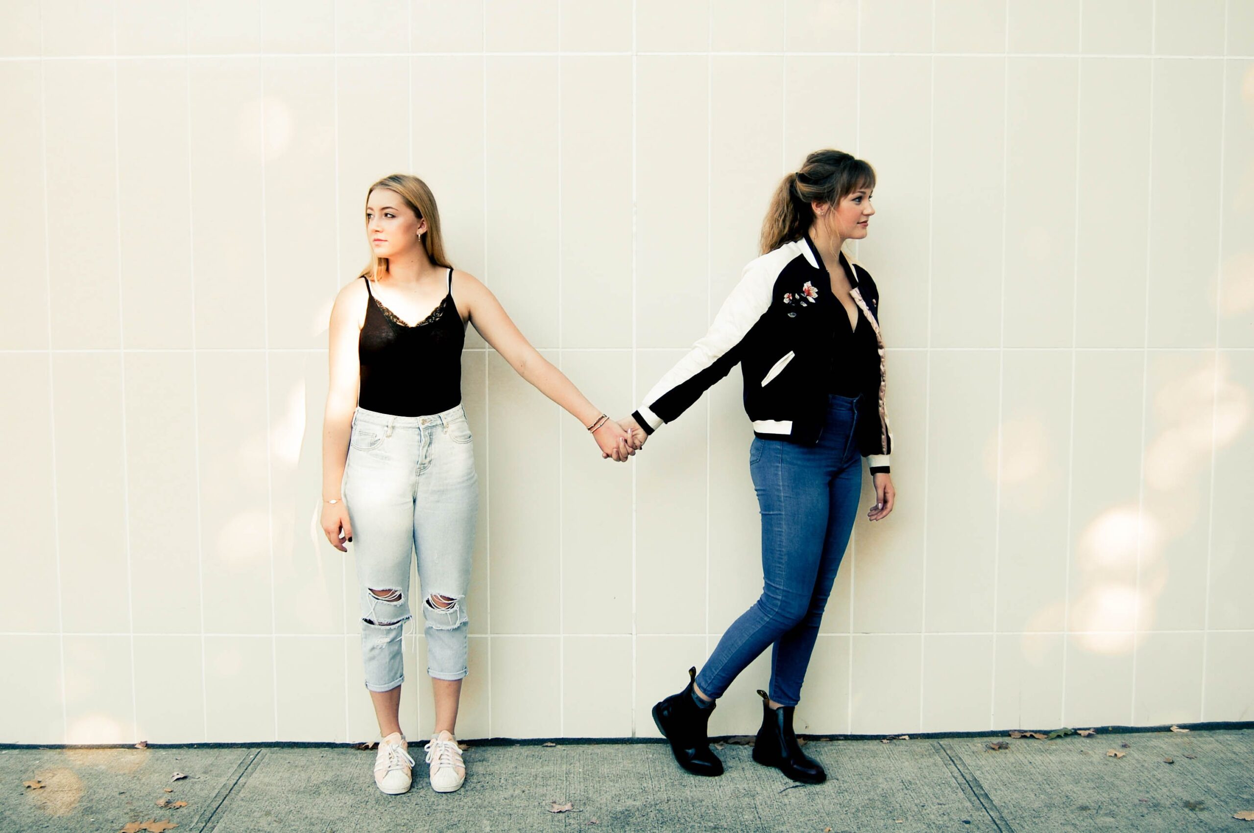 2 young girls holding hands but looking away from each other in a disconnected way